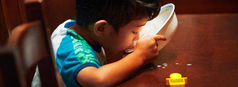Boy drinking milk out of a bowl